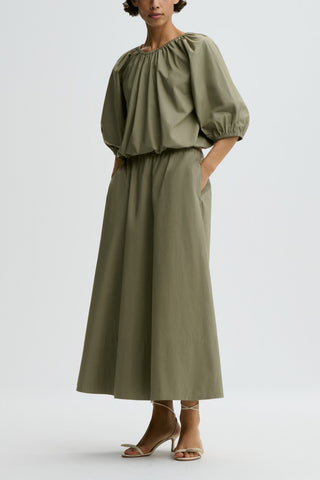By Malene Birger Lelow Blouse in Deep Lichen Green, featuring a voluminous silhouette in crisp organic cotton. This versatile top includes an elasticated neckline for on or off-the-shoulder styling, with puff sleeves and an elasticated hem.