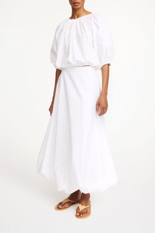 By Malene Birger Lelow Blouse in Pure White, featuring a voluminous silhouette in crisp 100% organic cotton. This versatile top includes an elasticated neckline for on or off-the-shoulder styling, finished with puffed sleeves and an elasticated hem.