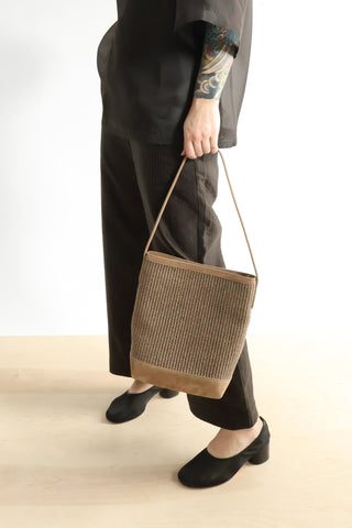 The Mansur Gavriel Small Everyday Cabas in Woven Anise is a luxury shoulder bag featuring a sophisticated woven texture and a structured leather base in a neutral earth tone. This designer tote offers a spacious interior and a slim, elegant strap, making it a perfect high-end accessory for both professional and casual daily use.