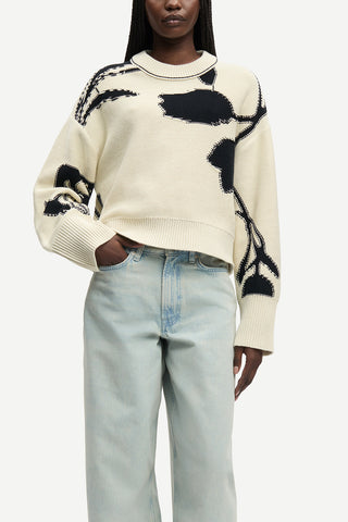 Samsøe Samsøe Salila Sweater in Cream Ashbloom, a heavy-weight jacquard knit featuring a bold black floral intarsia design and a relaxed cropped fit. This premium wool-blend pullover offers a modern, artistic silhouette that pairs effortlessly with high-waisted trousers for a chic cold-weather look.