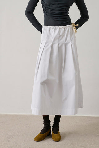 The Amalia Skirt in Blanc is a white organic cotton pleated midi skirt featuring a structural A-line silhouette and an adjustable drawstring waist. This versatile, elevated basic is a must-have for a minimalist summer capsule wardrobe.